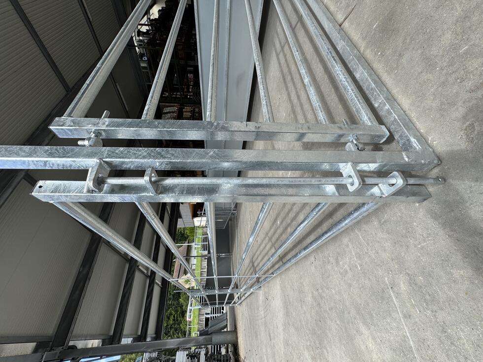 Ein Behandlungs- und Einfangstandstand mit Liegegitter und Schwenkachse, vorne zwei feste schwarze Räder, auf der Hinterseite ein schwarzes Brett, Schaf eingespannt umgedreht, wessen Klauen von einer Person geschnitten werden