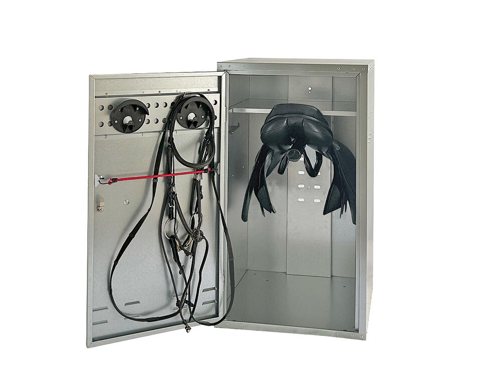 Ein Sattelschrank verzinkt geöffnet mit zwei Trensenhalter auf der Innenseite der Türe und ein Tablar im Hauptteil, resultierend in zwei Fächern, von welchen im grösseren und unteren zwei übereinander