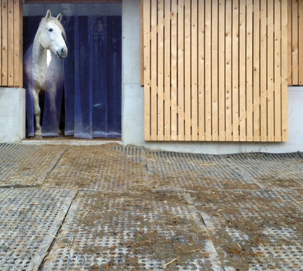 Zwei separate, schwarze Gummimatten nebeneinandergelegt, mit Kabelbindern verbunden, regelmässig angeordneten Löchern, sowie dreckigen Fussabdrücken zentral oben im Bild, Draufsicht